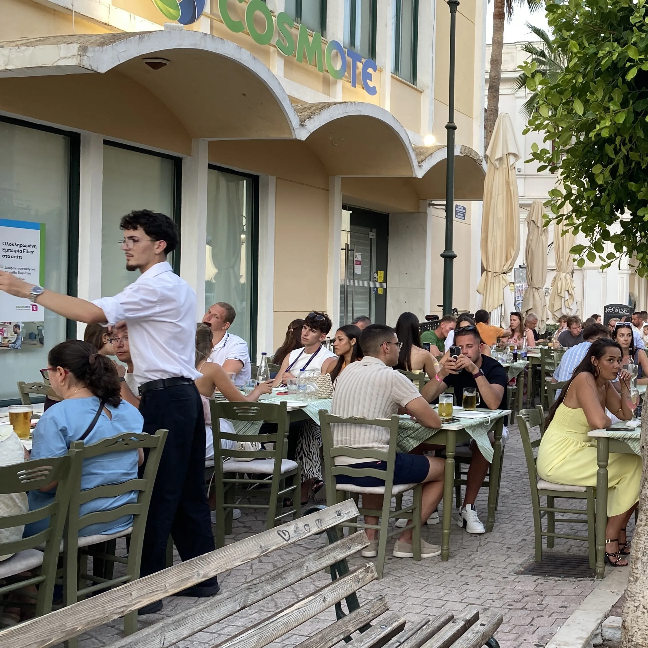 A waiter serving guests at Alektor's tables on the square